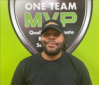 SERVPRO employee in front of green wall