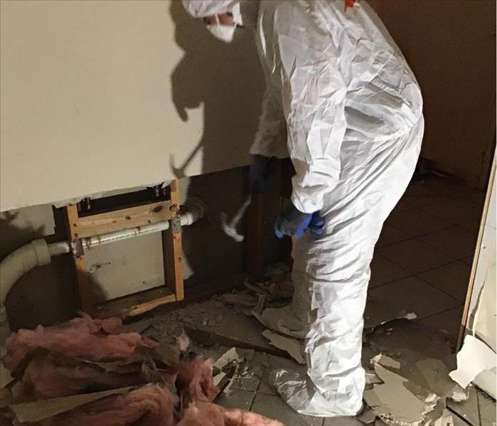 mold remediation expert wearing full PPE while removing water damaged insulation from home
